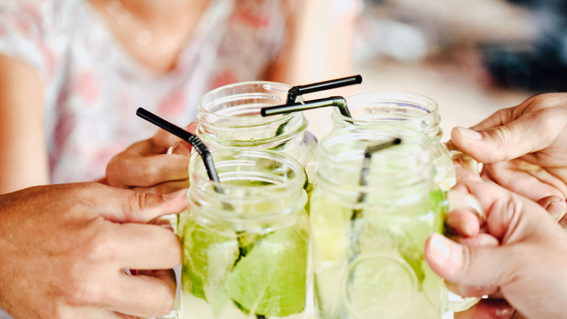Naiset kilistävät vihreillä yrteillä höystettyjä juomalaseja pöydän ääressä. 